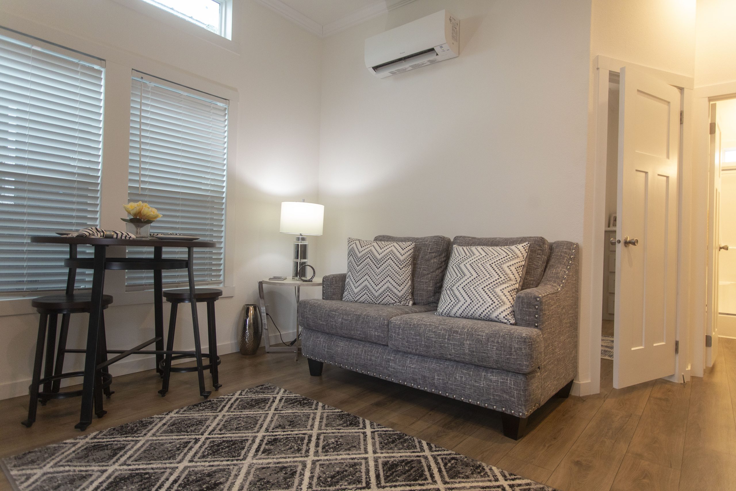 Tiny home living room just outside of Tyler Texas on highway 155 close to lake palestine, comfortable couch with table and chairs is seen with a designer rug.